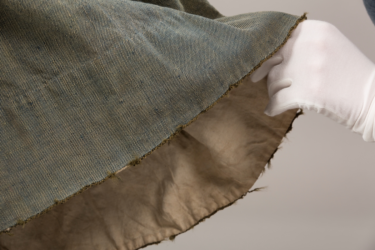 Form: Trangt liv med legg foran, skjørtet sydd med legg i livet.  God vidde i skjørtet, lange armer. Fem hekter i livet mangler.