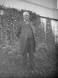 Hans Olson Mølmen står utenfor husveggen på Sygard Forr.