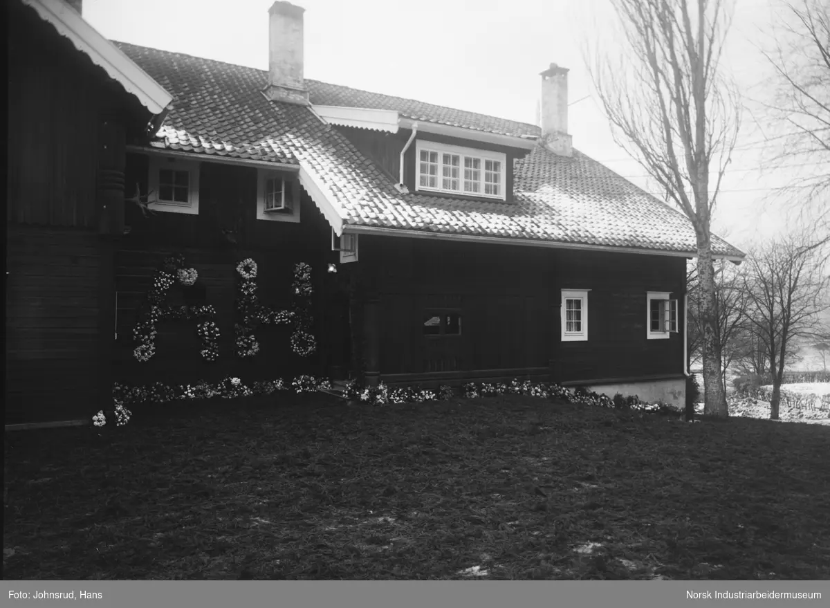 Hus pyntet med blomstermonogram i forbindelse med begravelse av Anna Holta.