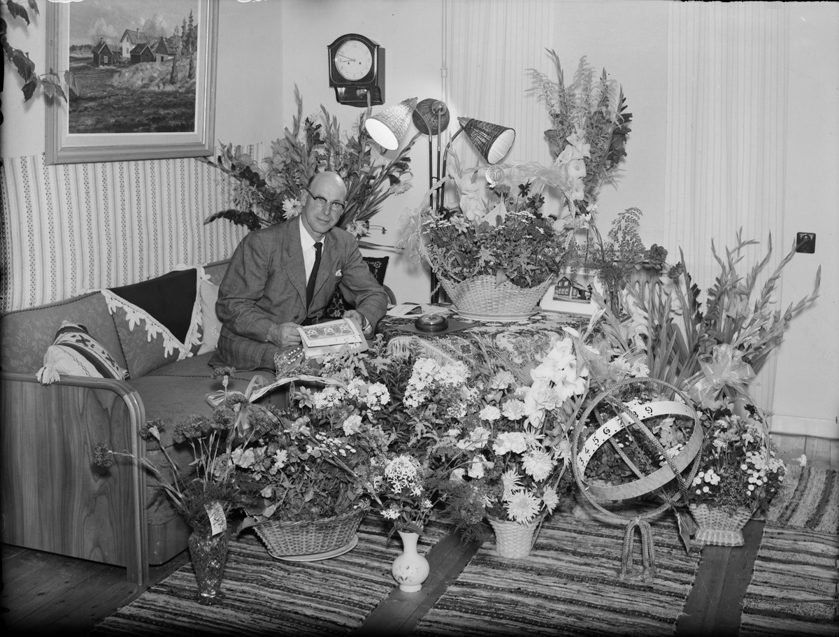Man i bostadsmiljö omgiven av blommor, Östhammar, Uppland