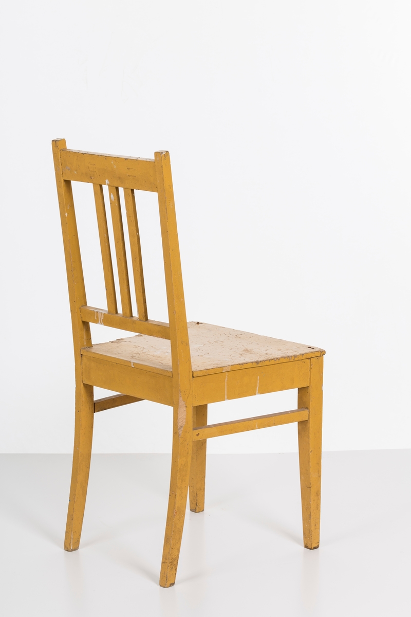 Stol i treverk, malt. Rygg med spiler. Den ene stolen har vært brukt betydelig røffere enn den andre.
