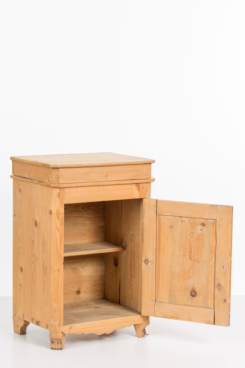 Toalettbord i ubehandlet tre. Det er rom for vaskebolle og skap under. Messingknott på døra til åpning og lukking, spor på innersiden av skapet kan tyde på at det tidligere også har vært en lås.