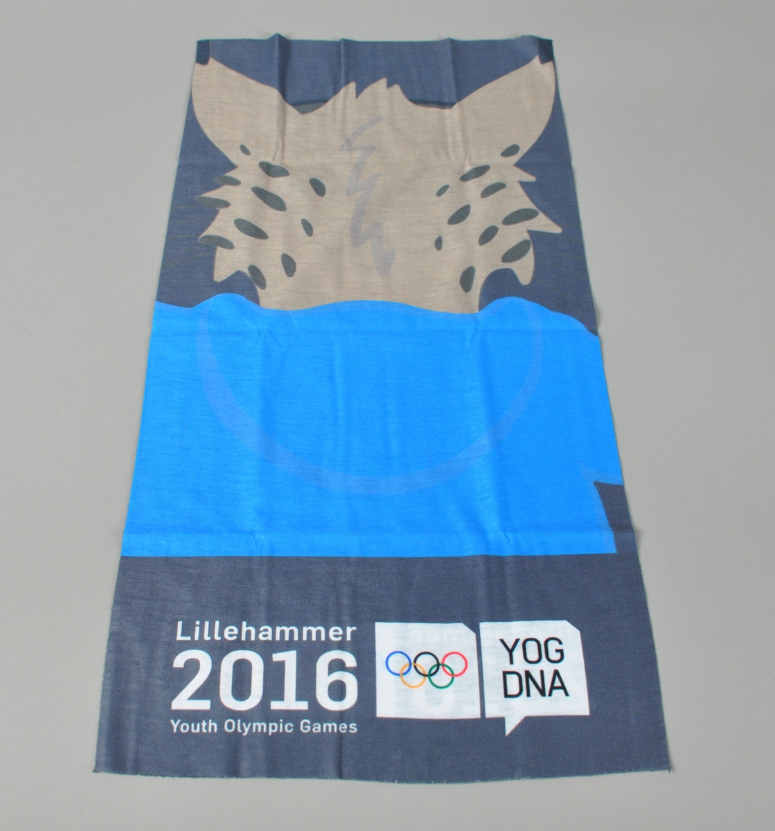 Buff - halstørkle - hodeplagg - sømløs tørkle for flere bruksområder. Blåmønstret ihht Ungdoms-OLs designprogram med logo for Lillehammer 2016 Youth Olympic Games og maskoten Sjogg.