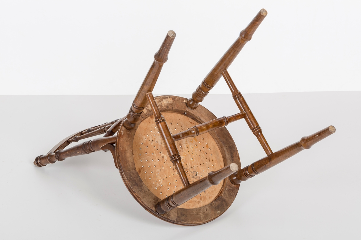 Stol i lakket treverk. Rundt stolsete med hullemønster. Rygg som er svakt buet med spiler og mønster. Dreide ben om spiler i rygg.