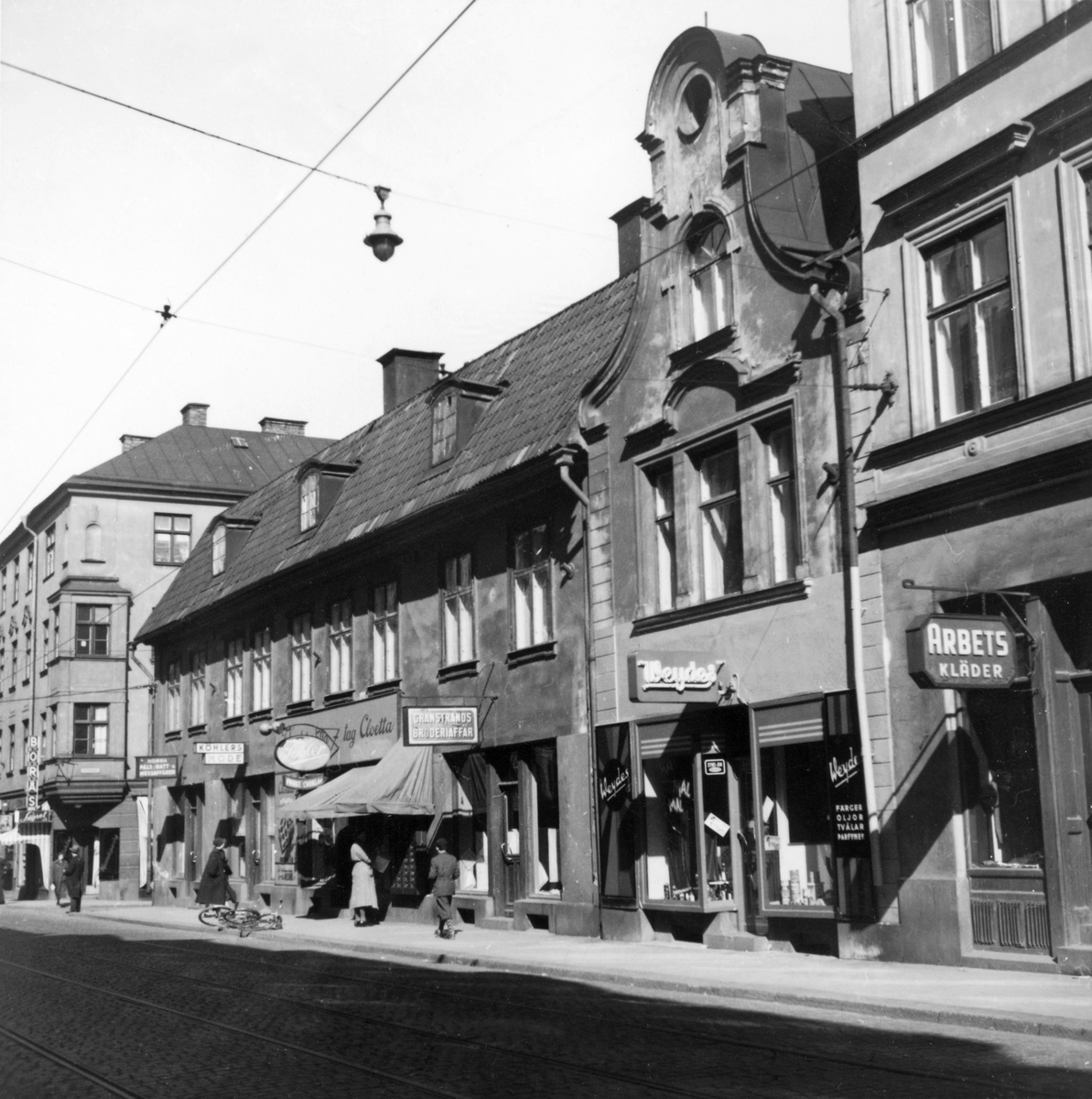 Vy mot Arnbergska gården på Kungsgatan i Norrköping. På femtiotalet var gatan en uttalad affärsgata och spårvagnen traffikerade även denna del av staden. 
På bilden ses sett urval av de affärer som låg här så som Toblers Frukt och Choklad, Köhlers Mode, Norra Päls - Hatt- & Mössaffären, Granstrands broderiaffär, Weydes, med mera.