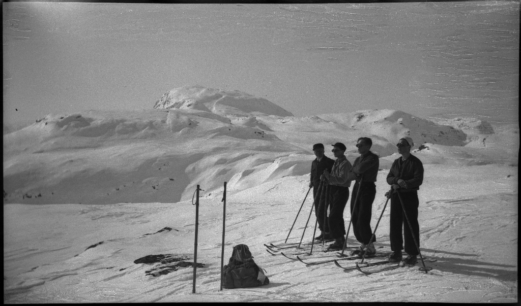 Fire unge menn på skitur fra Roalkvam til Stranddalen i Suldal. Det er bilder av hytter i fjellet, fra landskapet, lek med en hoppbakke og fra skigåing.