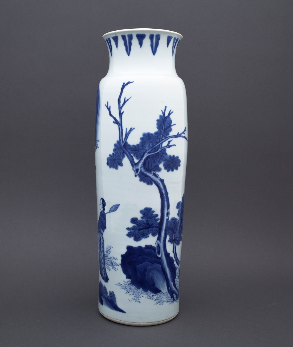 Tre mennesker står foran et stort tre. I bakgrunnen ser vi to fjelltopper. En mann står med foldete hender foran en annen mannsfigur. Han har skjegg, et sverd på ryggen og han holder i en vifte. Ved siden av mannsfiguren med sverd og vifte finner vi en kvinneskikkelse, som også holder i en vifte.