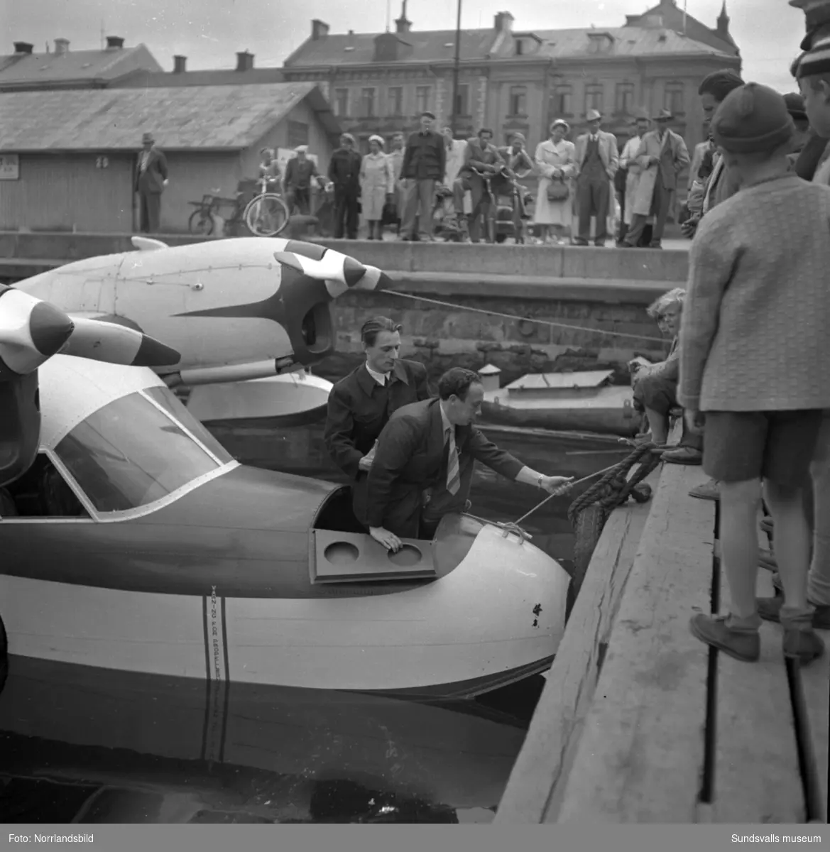 Många intresserade åskådare då Expressens tidningsplan på pontoner ligger förtöjd i hamnbassängen vid Tullgatan. Även bilder på planet ute vid Midlanda.