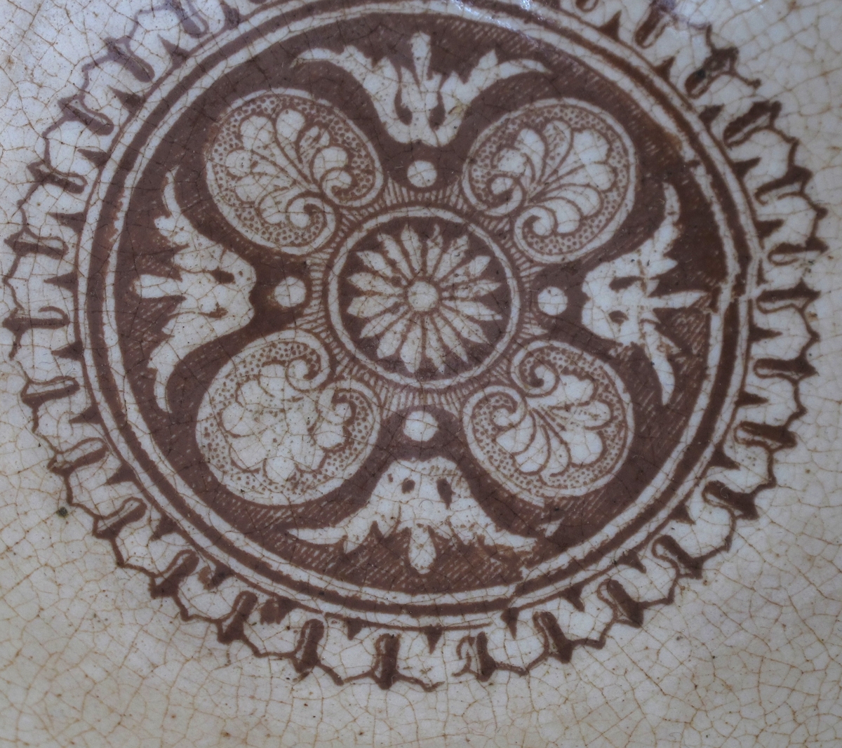 Bolle, stentøy, Buede sider, innsvunget fotring; trykt mønster i  brunt: Innv. og utv. bred ornamental bord m. skjell og "Garrya Eliptica" i bunnen lignende dekor, her er skjellene plassert i korsform i et rundt felt. Tilst. juli 1961: Krakellert.