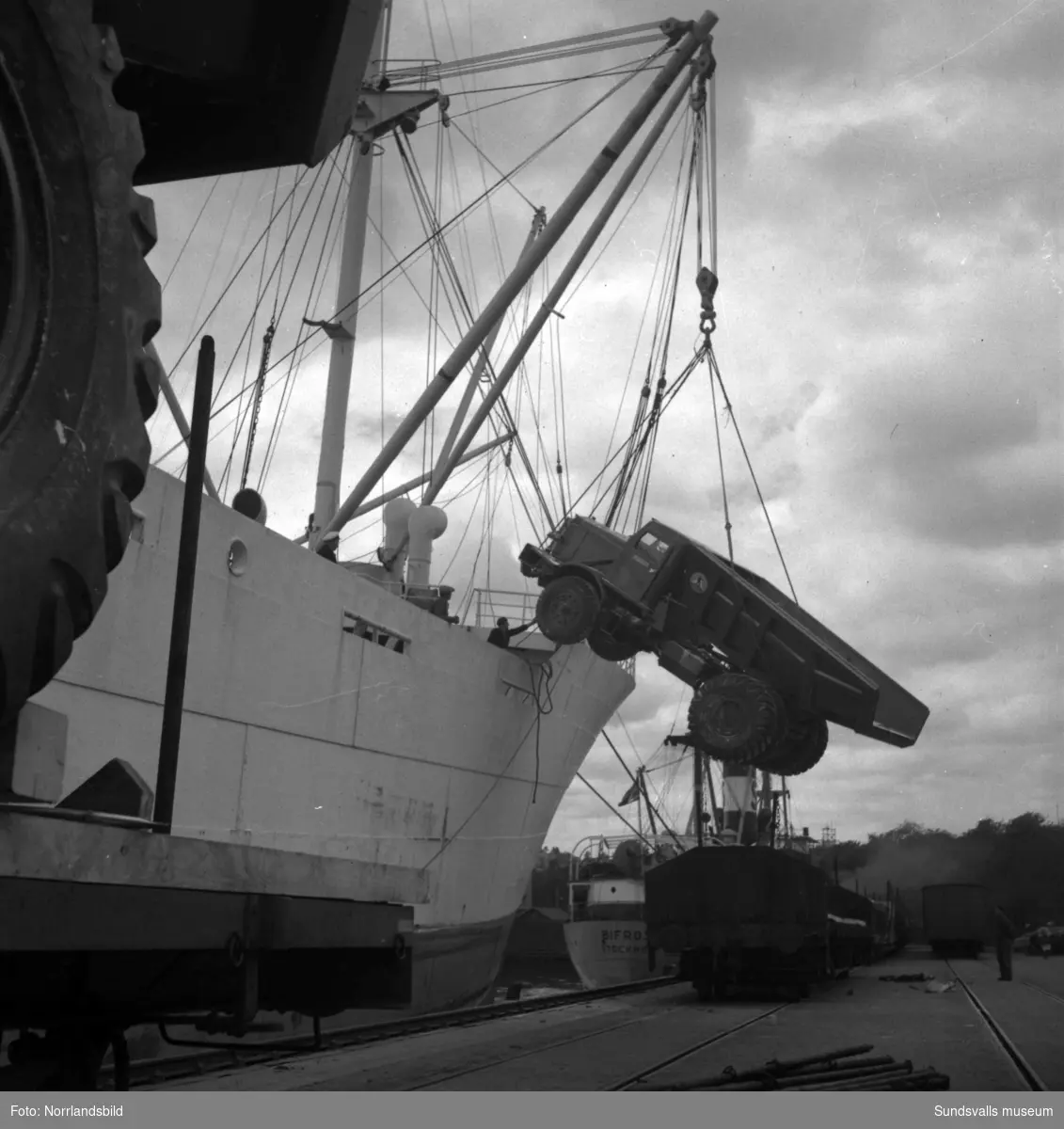 Stora truckar, eller lastbilar, lastas av från en ångare i Sundsvalls hamn.