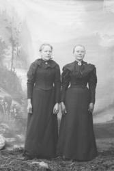 Portrett, 2 kvinner står ved siden av hverandre, helfgur. De