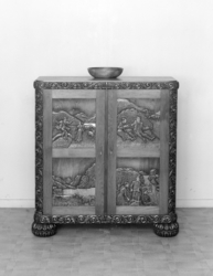 Skap med utskorne motiv på dørene.