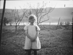 Liten jente, antakelig Ingerid Jorde, med trær og vann, anta
