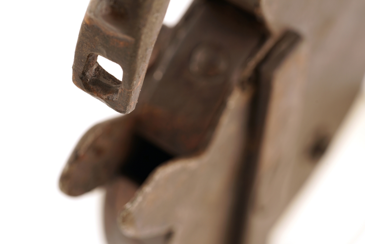 Hengelås, oval, av jern, med svingbart lokk over nøkkelhull. På det svingbare lokket er det inngravert; C 7.
Nøkkelen har firkantet skjegg og er blank.