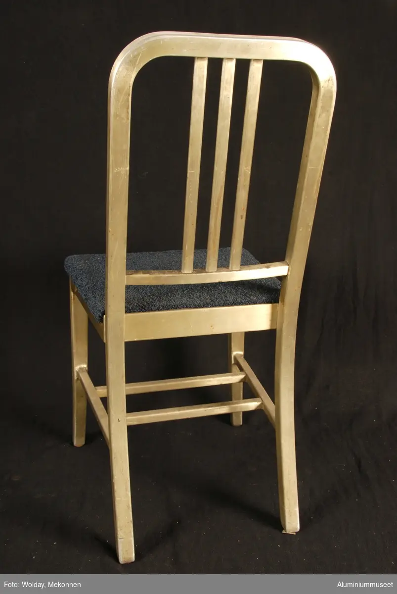 Teknikk: Stolen er delvis håndlaget fra Al-profiler. De er formet i bøyemaskiner og profilene er sveiset, eller skrudd sammen.
Form: Valig spisestuestol-fasong

Under setet er det beskrevet hvordan den skal vedlikeholdes. Artikkelnummer ol.