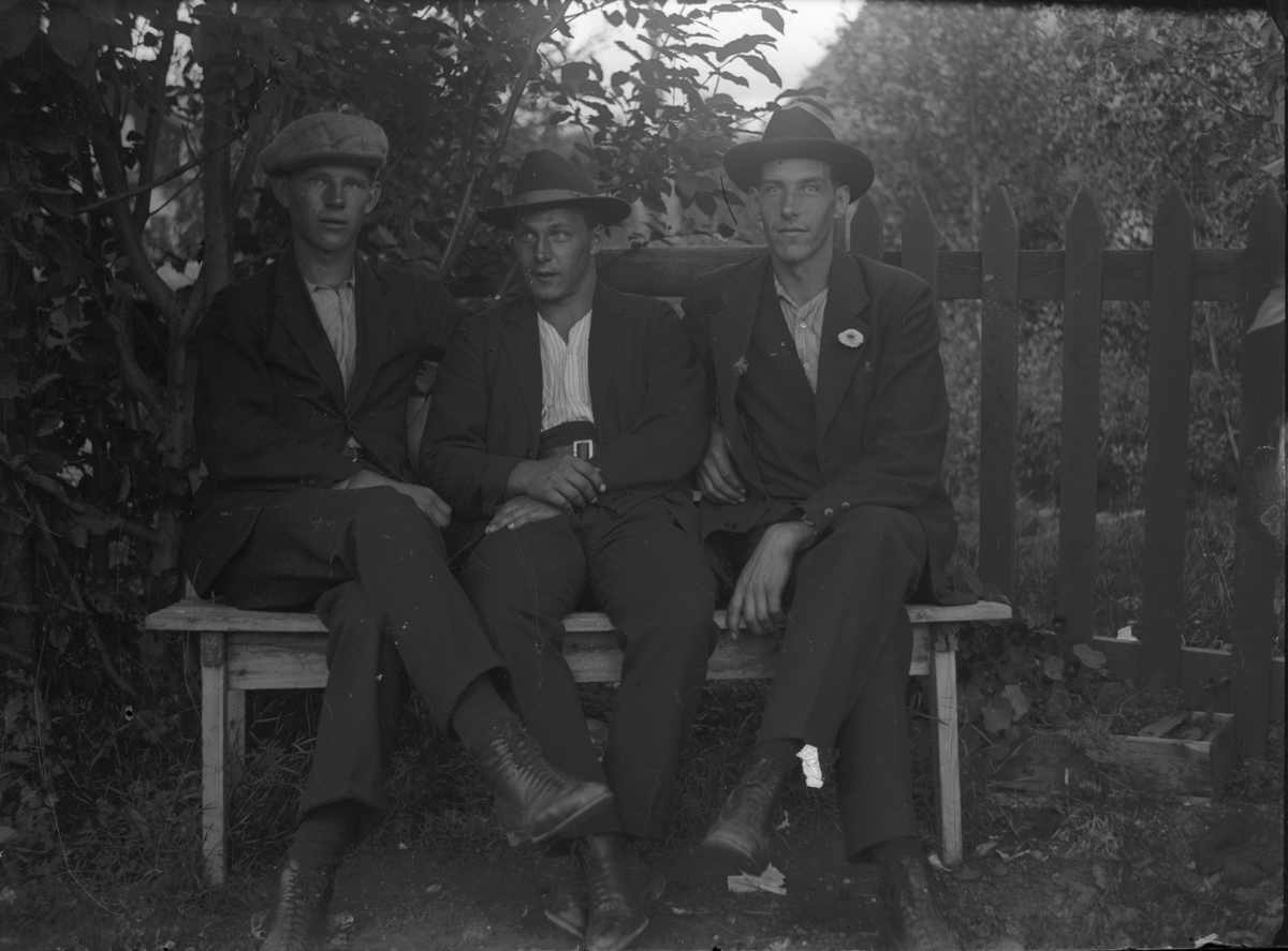 Tre män på en bänk.