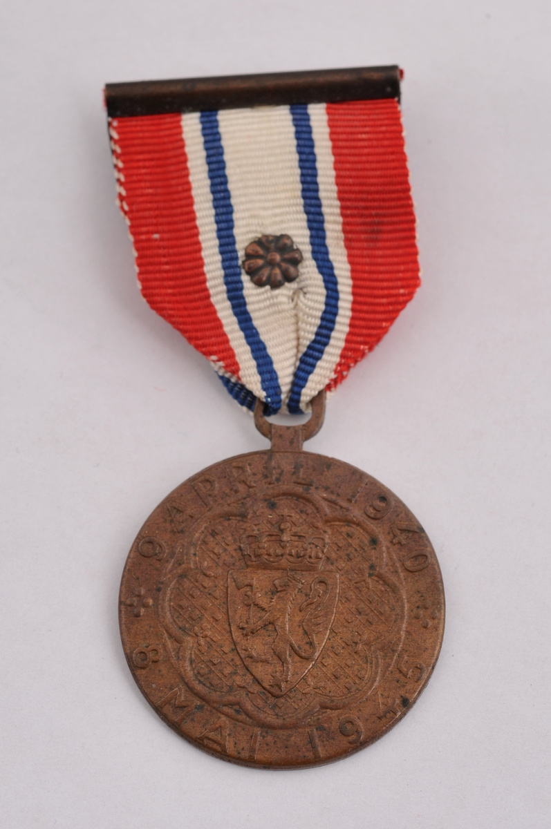 Medalje i bronse, med band i flaggfargane og rosett midt på. På framsida av medaljen er riksvåpenet, på baksida eit vaiande flagg og ei broten lenkje.