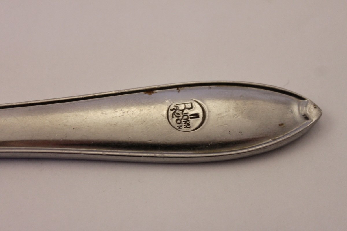 En bordskniv i rostfritt stål i modellen gammal svensk och med logan för stugbyn på Södra Björnön. En cirkel med en kvist vari det står Björnön.