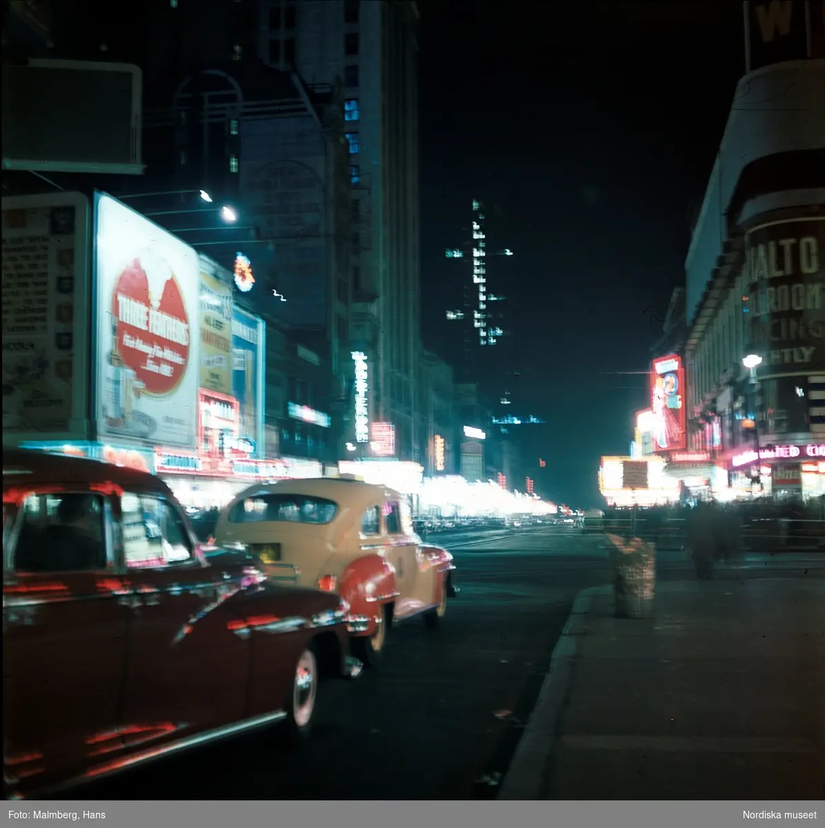 New York, USA. Biltrafik på gata i kvällsbelysning. Neonskyltar, reklam.