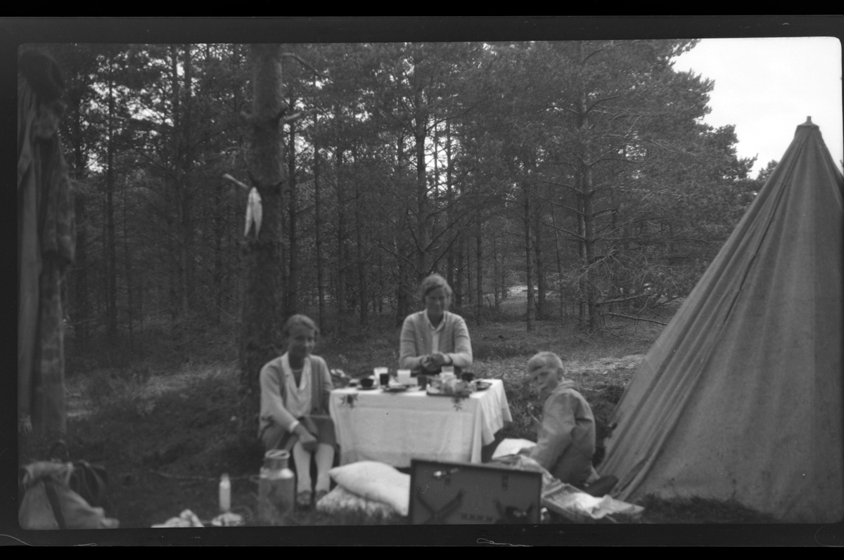 Lillemor Nickelsen, Lise Skabo og Rolf junior Sundt spiser og drikker utenfor et telt i Furulunden ved Mandal.
