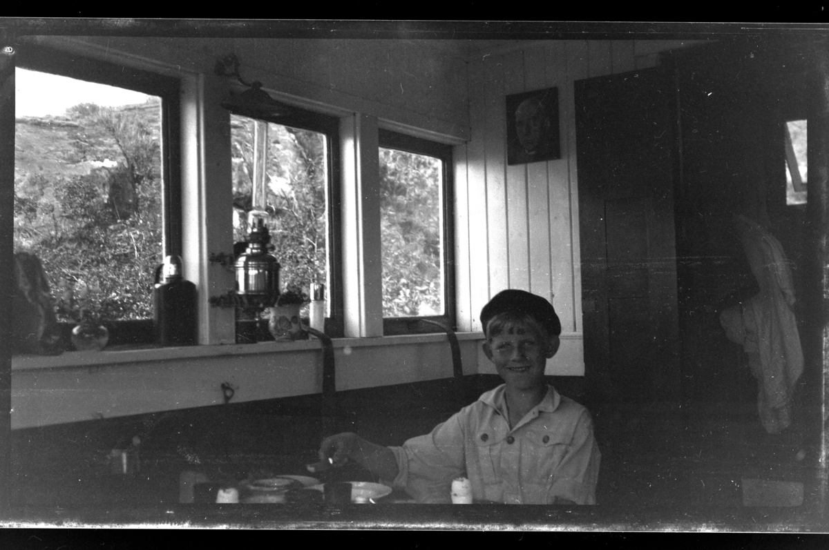 Rolf Sundt Jr. i stue i hytte på Søndre Hald i nærheten av Loshavn. Fotografert juli 1932.