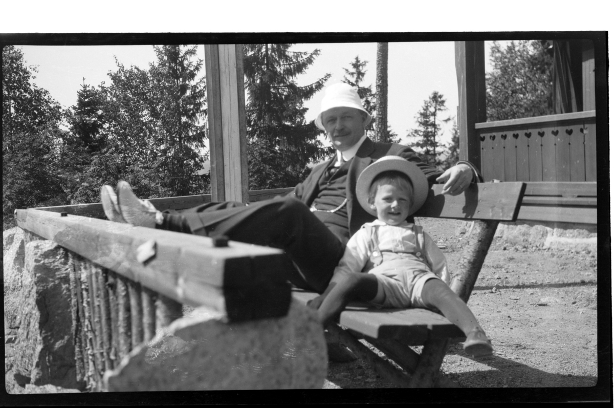 Julius Thaulow Aubert Sundt sitter på en benk sammen med sin morfar Julius Sundt, Villa Knyggen. Fotografert 1920.
