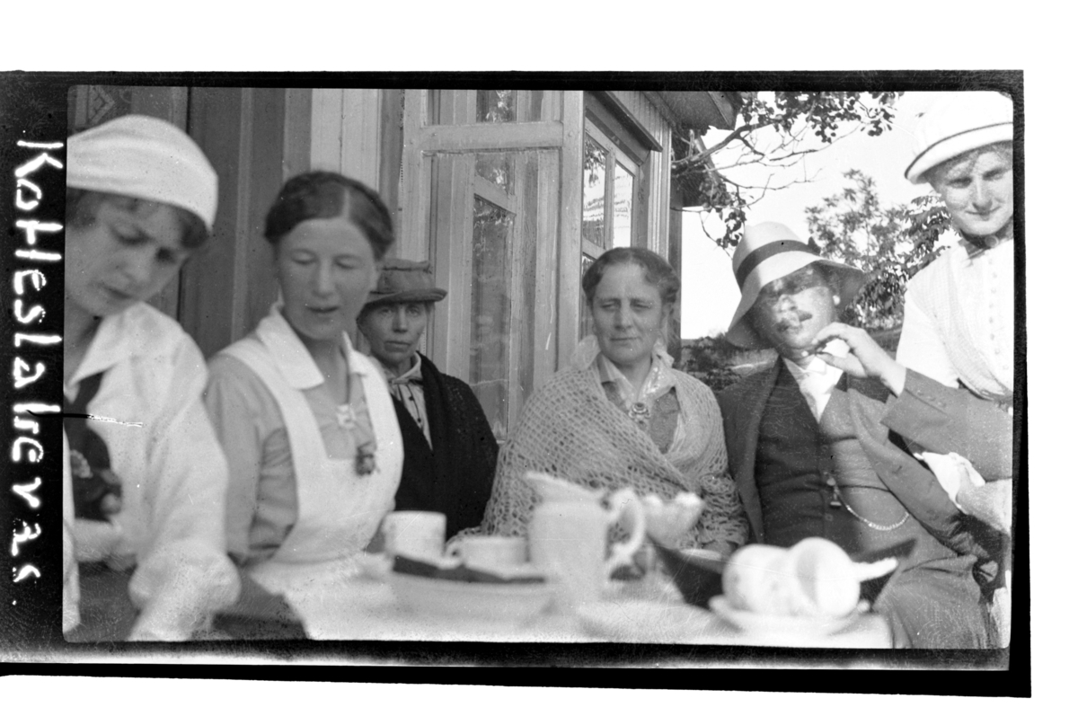 Birgit Aubert, en barnepleierske, Julie Myhre, Birgitte Aubert, Julius Thaulow Aubert, Hilda Sundt, drikker kaffe på verandaen, Hvasser. Fotografert 1917.