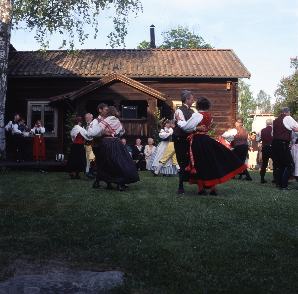 Nationaldagen i Bollnäs 6 juni 2001. Folkdansare och publik utanför en gammal timrad gård.