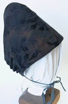 "Kammamössa" av siden med grovt linnefoder, sydd av två delar med en söm över nacken. Ett blått linneband är draget genom en sydd kanal nertill.