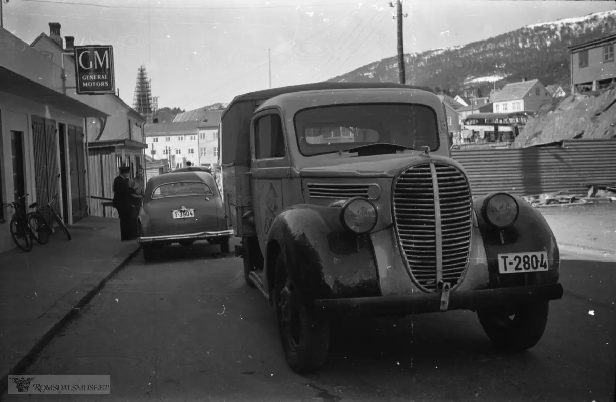"1956"."Bilkolisjon ved Bergsbak".Lastebilen T-2804 er en Ford 1939 modell..Lastebilen tilhører margarinfabrikken, som hadde tilhold i brakken foran Lørva. Smør Hagen eide den.