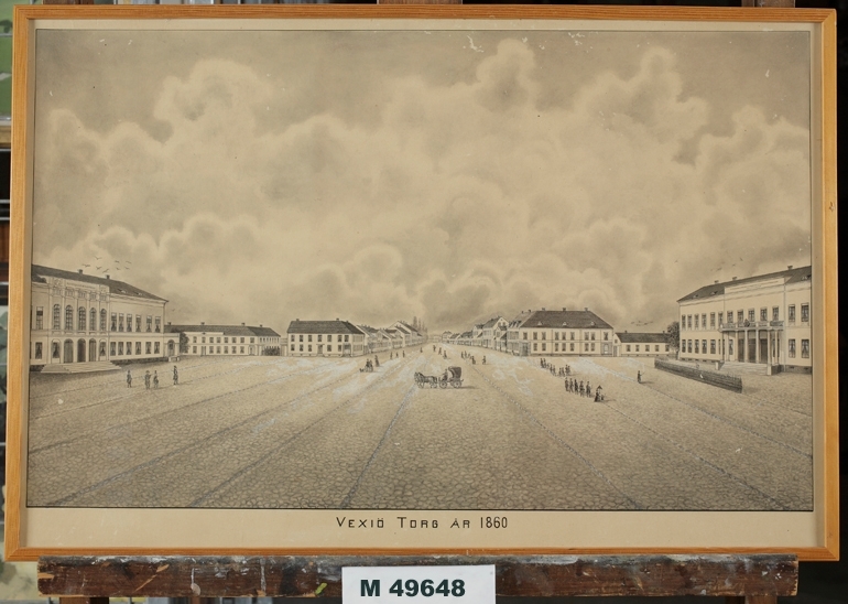 Litografi.
Stor litografi föreställande Växjö torg (Stortorget) år 1860, mot väster.
Till vänster syns Stadshotellet och till höger Residenset.
Verkar delvis ha varit färglagd (handkolorerad) från början.