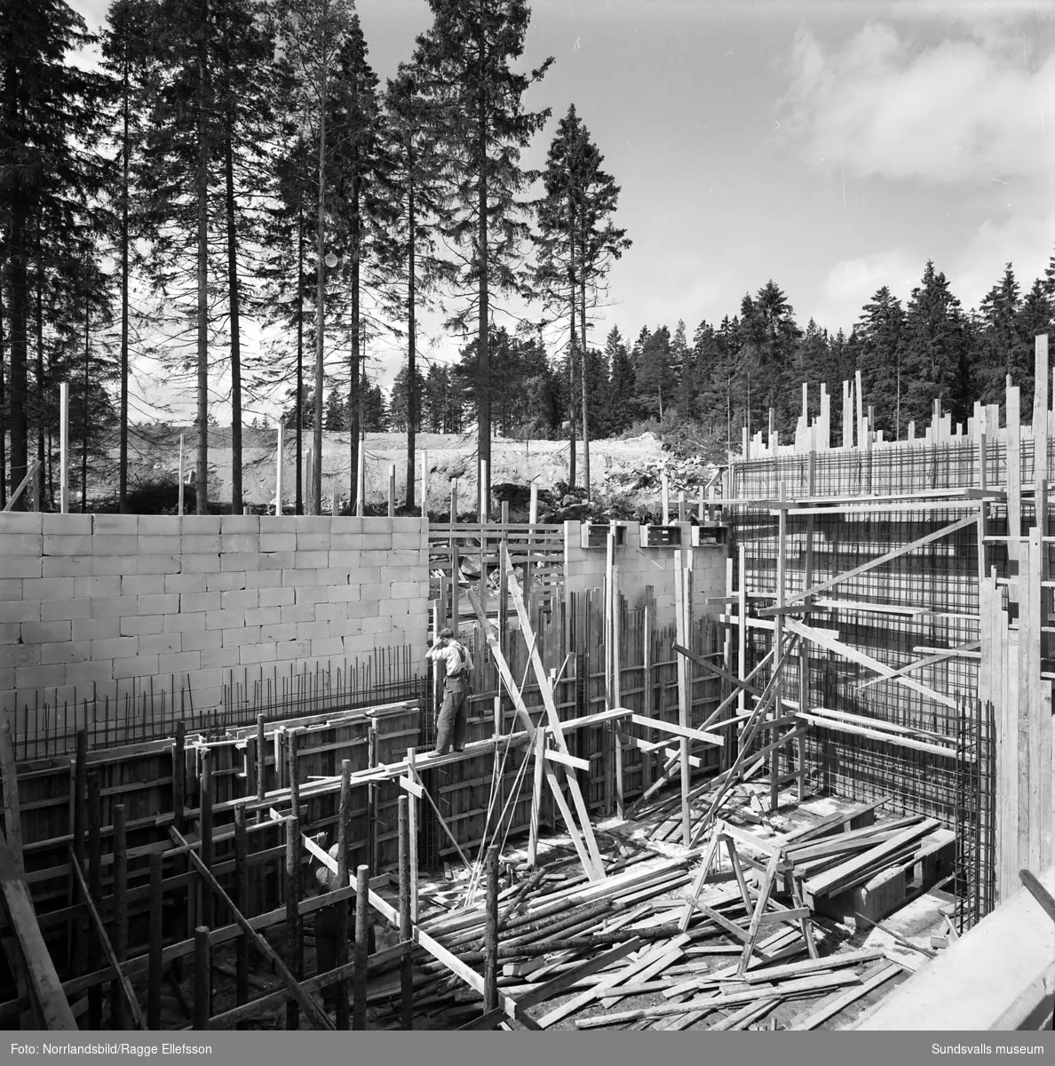 Takstolarna lyfts på plats vid bygget av Nyhamns kraftverk. En del av arbetarna är mer än lovligt våghalsiga och till synes helt bekväma med att arbeta på hög höjd.