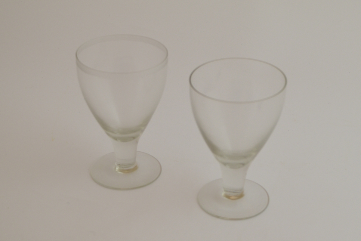 To glass. Rund fotplate, stett uten dekor. Et glass har klokke uten dekor, og et glass har dekor av en stripe nedenfor munningssranden.