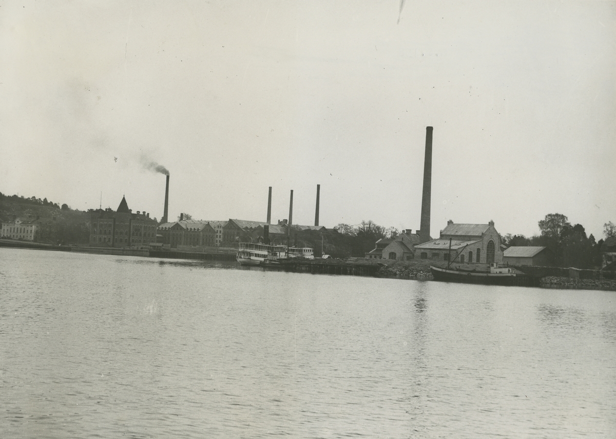 Vy mot Kattholmens kraftverk, till höger i bakgrunden syns Huvudkontoret. Kraftstationen stod klar 1905 och inrymde två ångturbiner av De Lavalfabrikat. Ångturbinerna levererade elström till fabrik och samhälle från 1905 till 1921 (Arvidsson m fl, 1997:88).