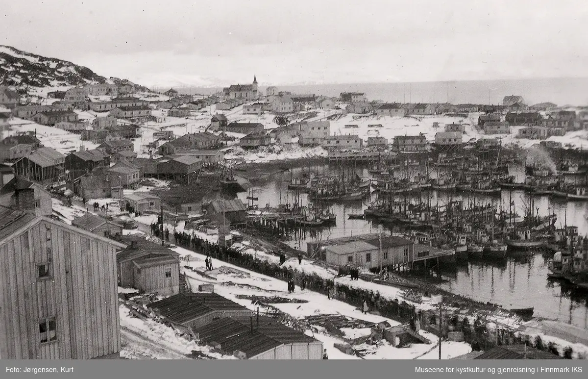 Gjenreisning. Honningsvåg med brakkebebyggelse og fiskeflåten i havn. I bakgrunnen Honningsvåg kirke. 1. mai 1947.