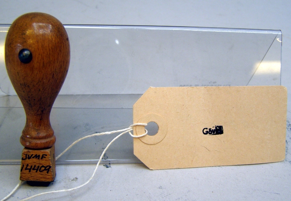 Stämpel med rektangulär stämpelplatta av gummi och svarvat brunt träskaft.
Text: "Gävle".