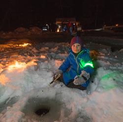 Bilde av gutt som fisker med pilkestikke i hull på isen på s