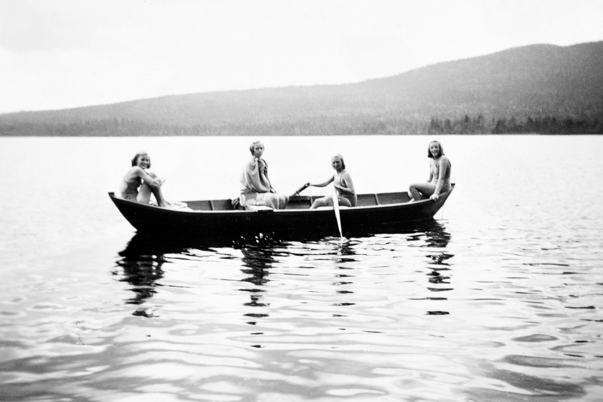Friluftsliv under 2. verdenskrig.  Fotografiet viser fire badende elverumsjenter i båt på Rysjøen i Trysil (Søre Osen).  Jentene hadde syklet til ei hytte ved denne sjøen for å få et avbrekk fra hverdagen og for å kunne glede seg over sosialt samvær med hverandre.