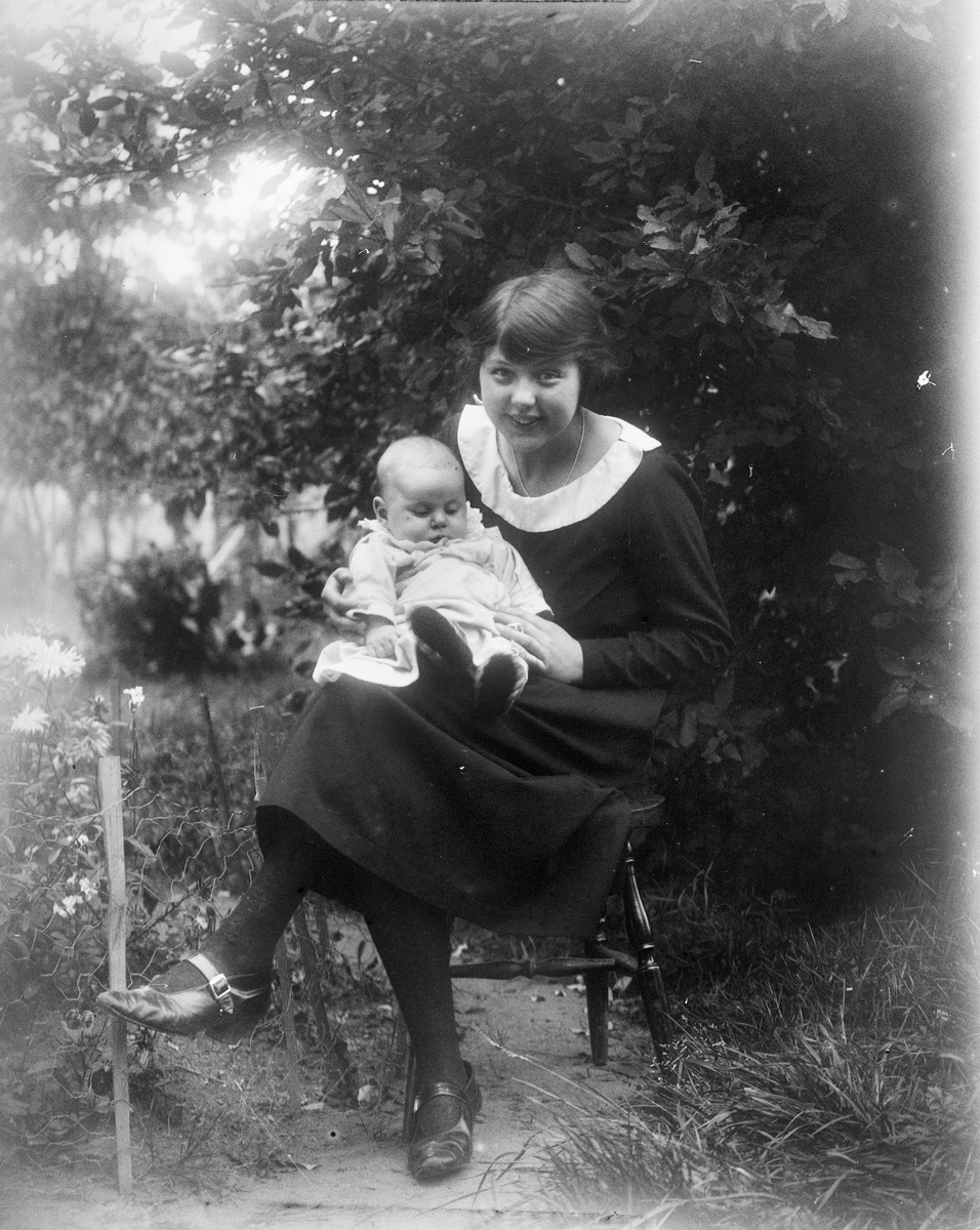 Ung kvinna sitter med Tore Alinder i knät, Sävasta, Altuna socken, Uppland 1924