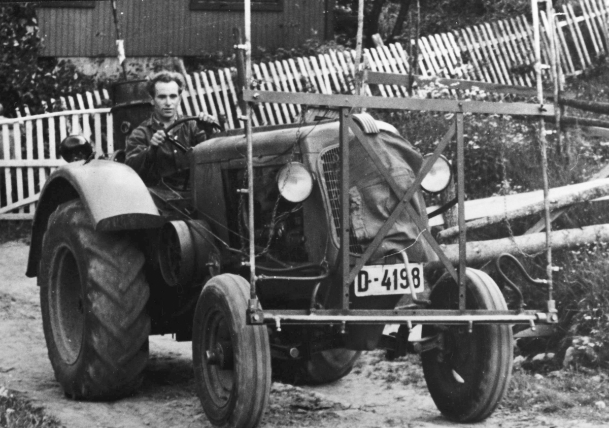 Oliver Standard 70 traktor D-4198 blir kjørt av Olav Nytrøen 1924-1998. Traktoren er påmontert sprøyteutstyr.