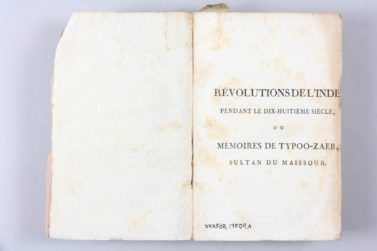 Bok, pappband, "Révolutions de l´Inde", del 1, tryckt 1796 i Paris. Pärmar av ljusbrunt papper, blekt rygg med tryckta etiketter med bokens titel och nummer, otydlig text. Skuret snitt.