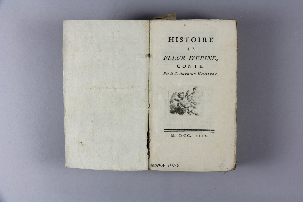Bok, pappband, "Histoire de Fleur d'Épine, et Oeuvres mêlées en prose et en vers", skriven av Hamilton, tryckt 1749.
Pärm av gråblått papper, oskurna snitt. Blekt rygg med etiketter med titel och samlingsnummer.