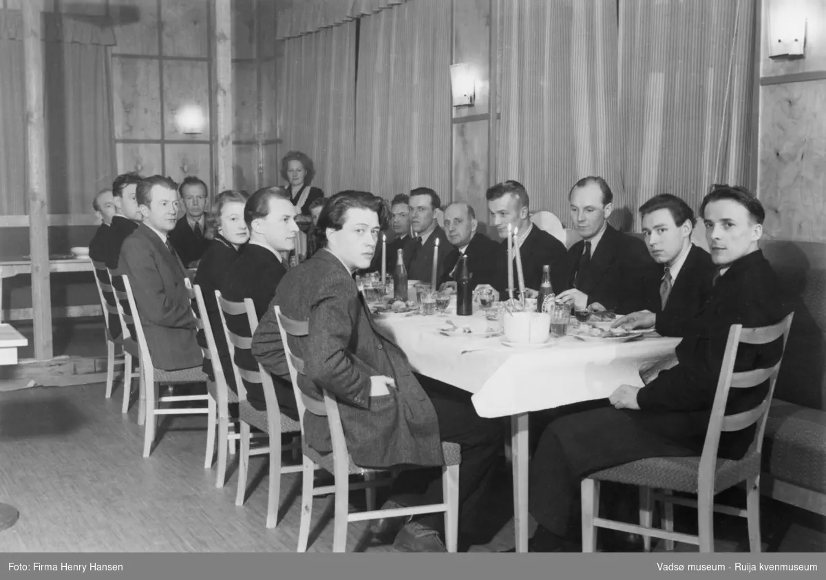 Menn og noen kvinner samlet rundt et festbord (Bjørn Sannes, Nils Fr. Jørgensen, Wara.G., Melsvik, Ingvald Ofstad, Bergljot Isaksen - Kilde VAM.F01_247)
