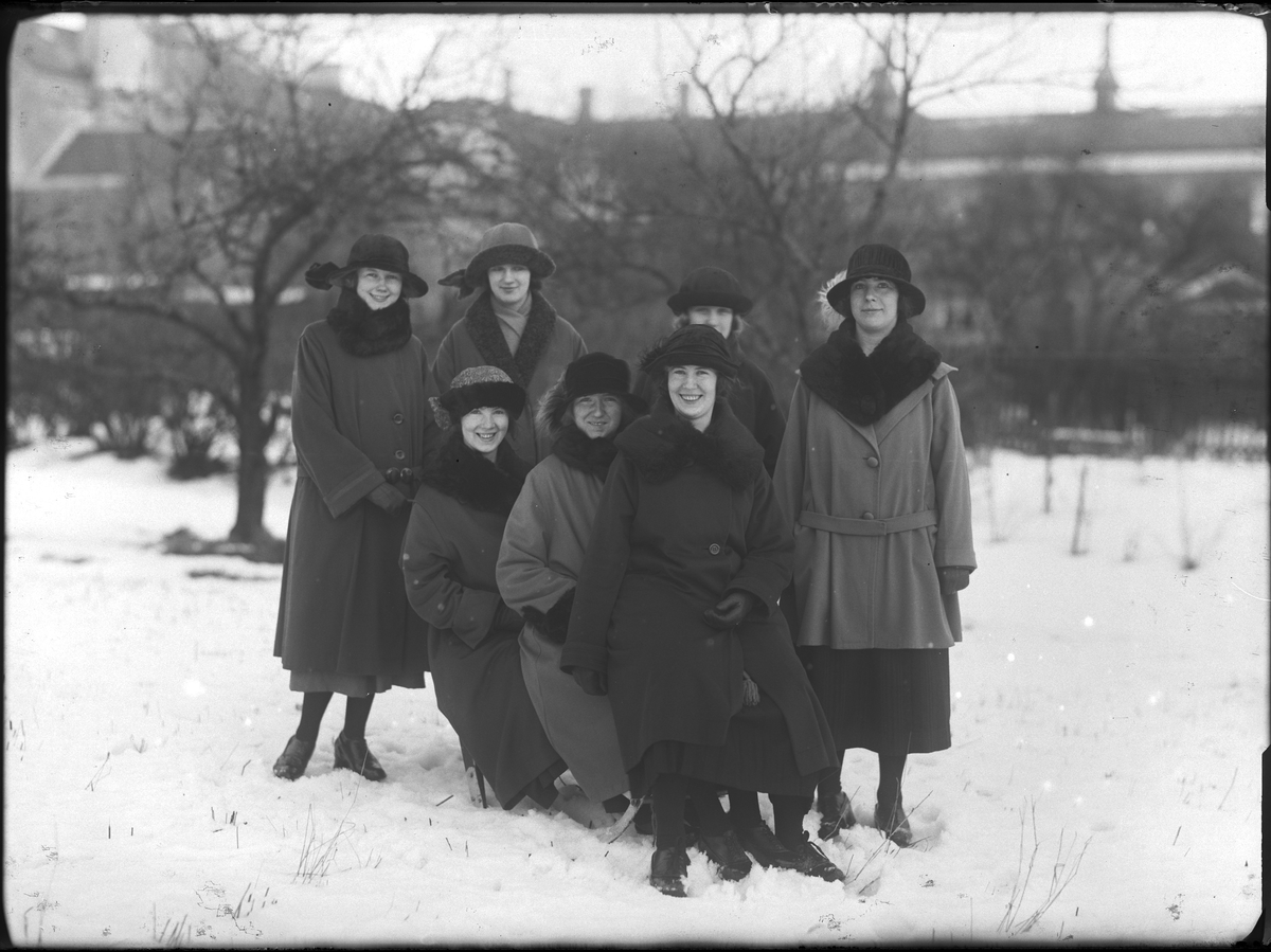 Gruppbild med sju kvinnor klädda i vinterkappor och hattar fotograferade ute i snön. Tre av dem sitter på en spark medan fyra står runt dem. Längst bak på sparken sitter Lisa (efternamn okänt) och längst till vänster, bakom henne, står Lilly Johansson.