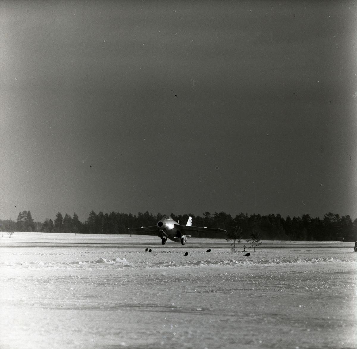 Ett startande plan av modellen J29 Tunnan i Söderhamn den 16 januari 1957. På marken finns några orrar.