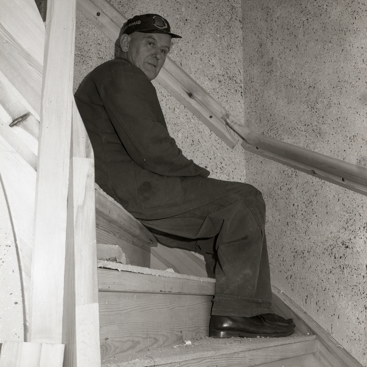 En man sitter i en trappa där väggarna är stänkmålade, 1967-68 vid gården Sunnanåker.