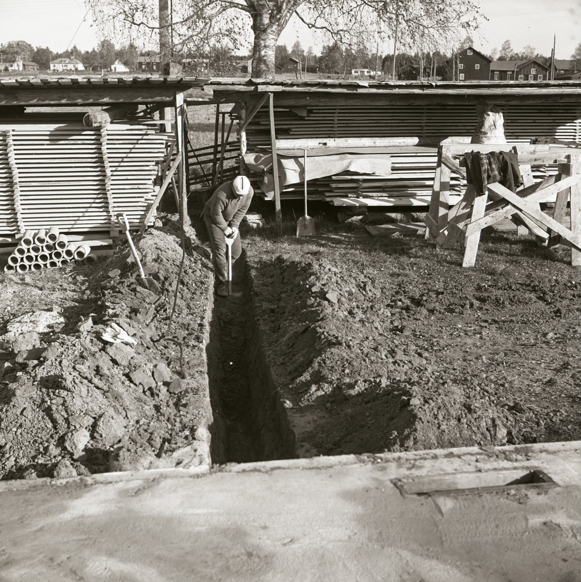 En man gräver ett dike för nedläggning av avloppsrör under byggnationen av ett bostadshus vid gården Sunnanåker, 1967.
