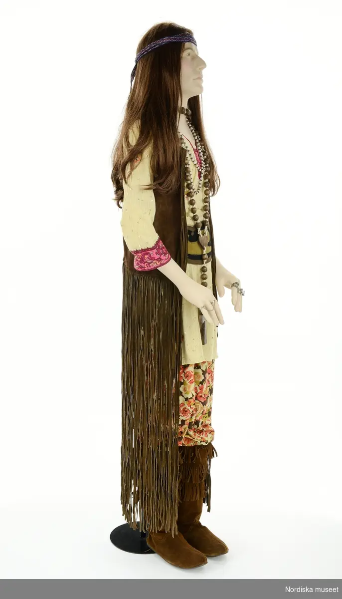 Hippie 1960, från utställningen Modemakt. Modellen är fotograferad för 360-visning. Information om kläderna se Relaterade objekt under Referenser. Tunika och hårband är rekvisita.