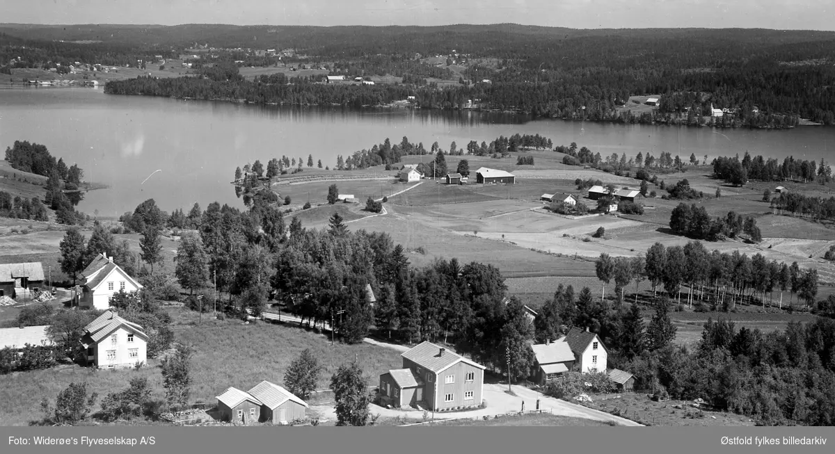 Lønnberg 66/3 - 67/30 med Sandem skole til venstre. Rømsjøen i bakgrunnen. Flyfoto fra Rømskog.