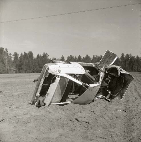 En skrotig, vält bil ligger på en åker, Glössbo 1968.